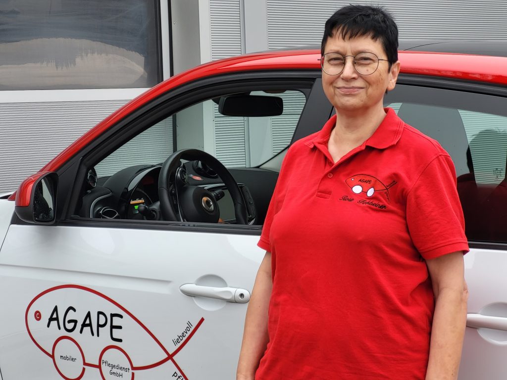 Mitarbeiterin des AGAPE Pflegedienstes am Fahrzeug